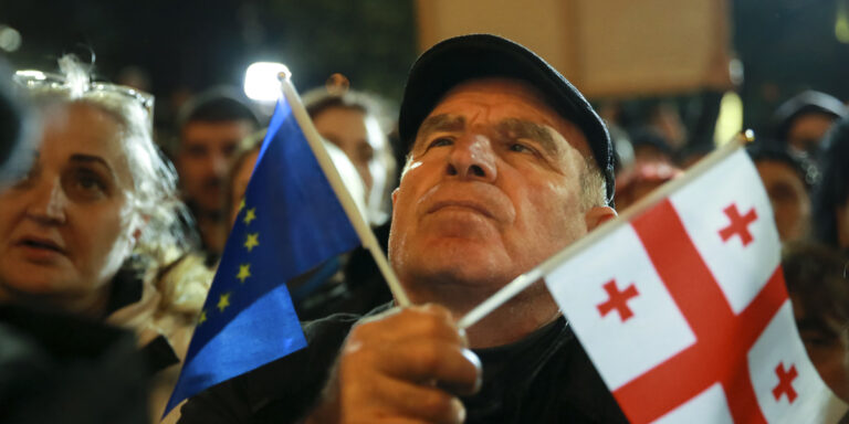 En demonstrant håller en EU- och en georgisk nationalflagga