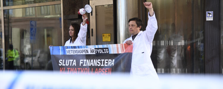 två forskare med knuten näve och plakat