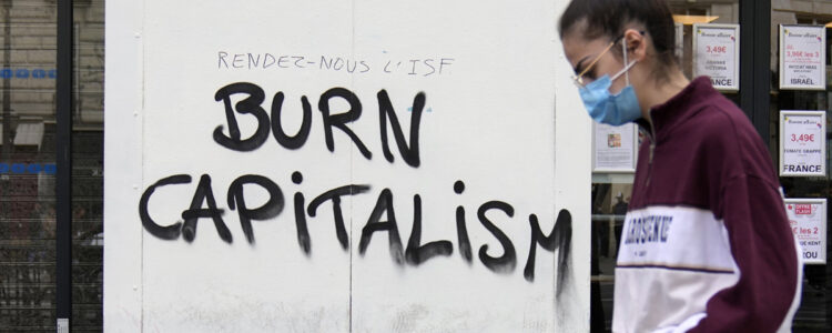 Person går förbi klotterad text som lyder Burn capitalism.