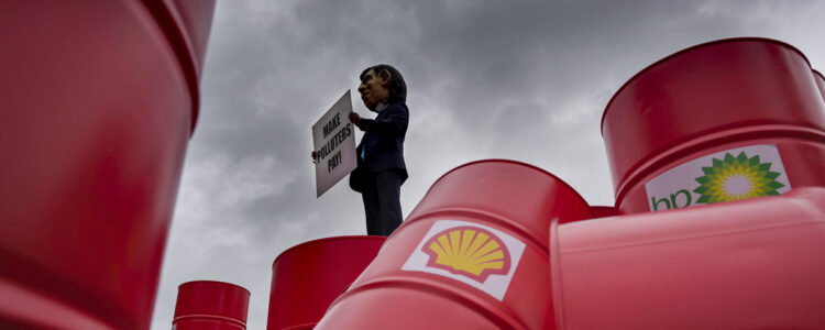 Oljetunnor märkta Shell och man med plakat