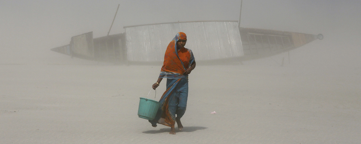 kvinna bär hink med vatten i sandstorm