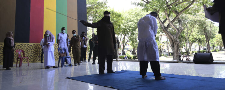 man piskar en annan man medan folk ser på