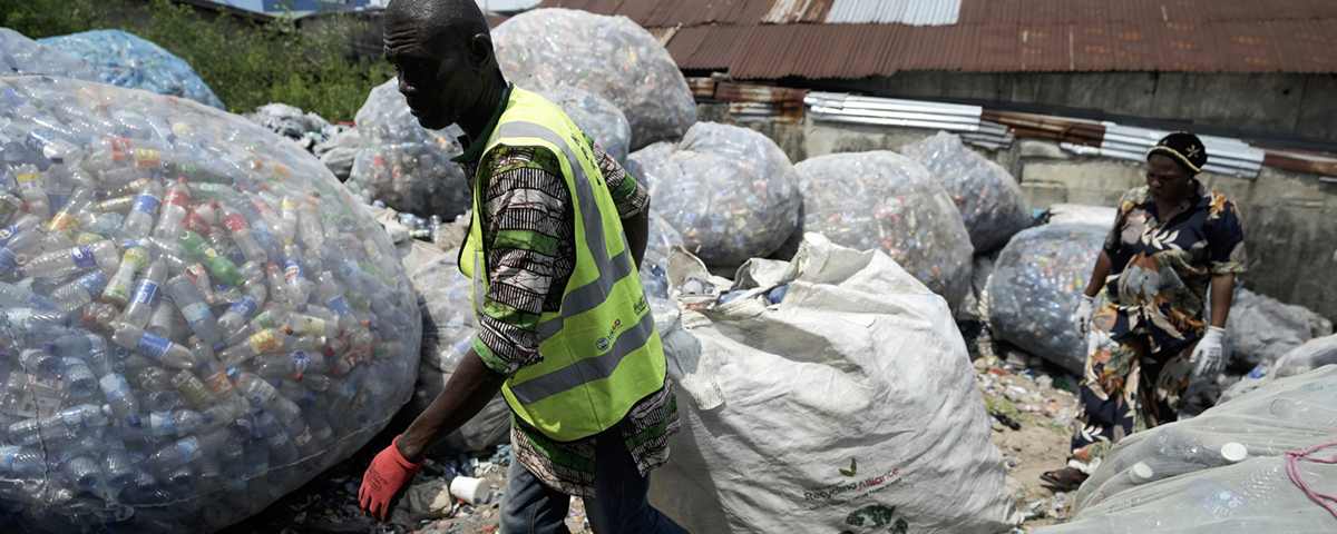 man dra stor säck med plastflaskor på soptipp