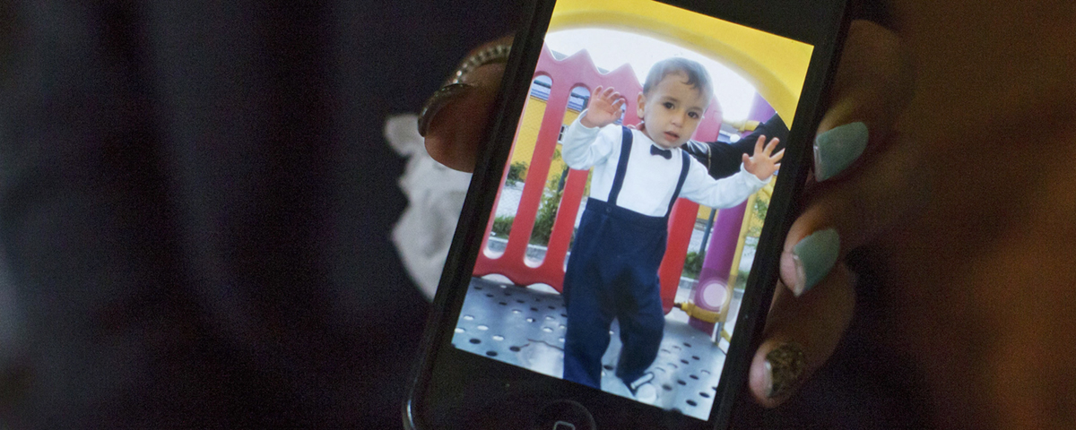 alan kurdi i finkläder på mobilskärm