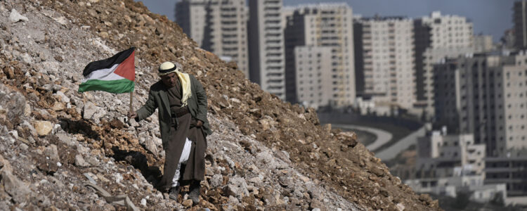 En äldre palestinier går i grushög utanför stad