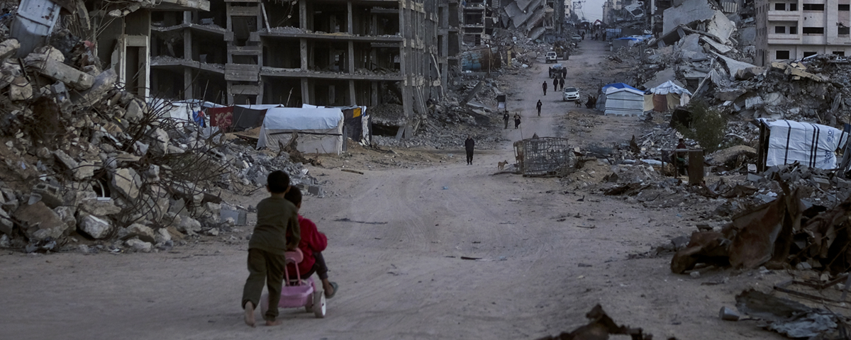 barn går i sönderbombad bebyggelse