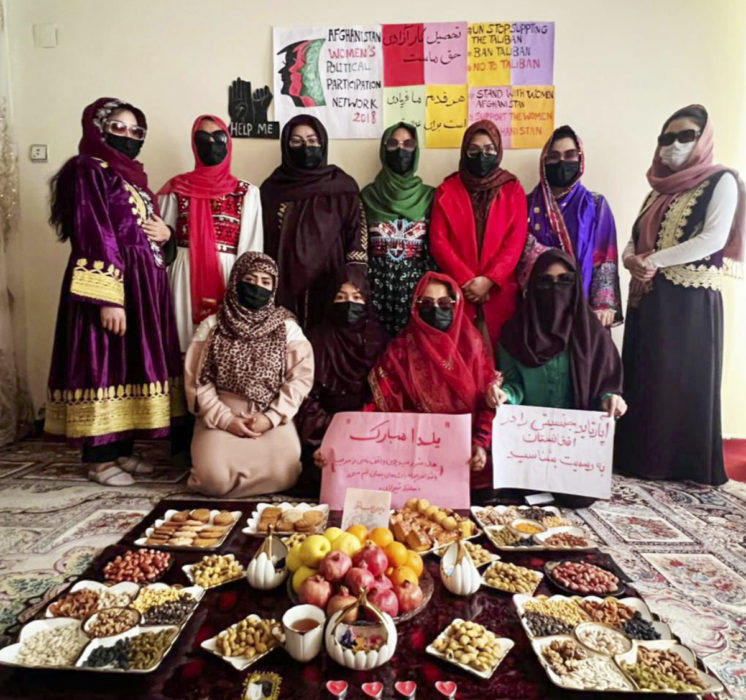Afghanska kvinnor står framför ett uppdukat bord.