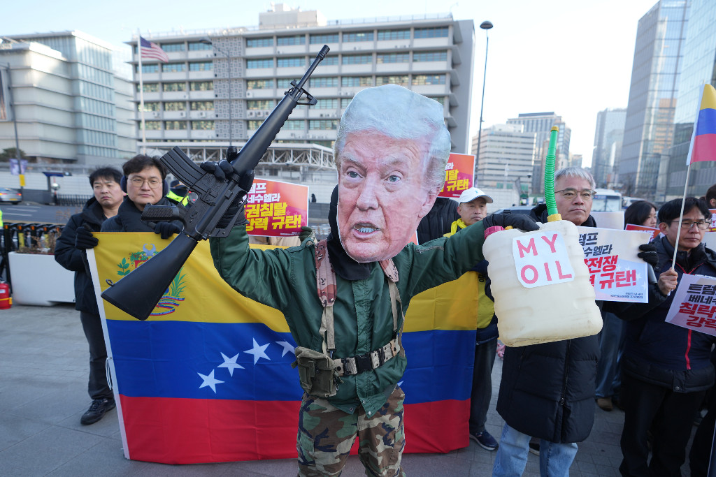 Demonstrant bär pappmask med Trumps ansikte på, håller upp ett låtsasgevär och ett plakat med orden ”min olja” på.