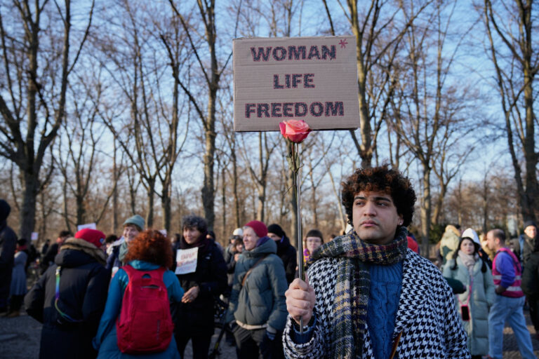 Demonstrant håller i ett plakat med texten kvinna, liv, frihet, på engelska.