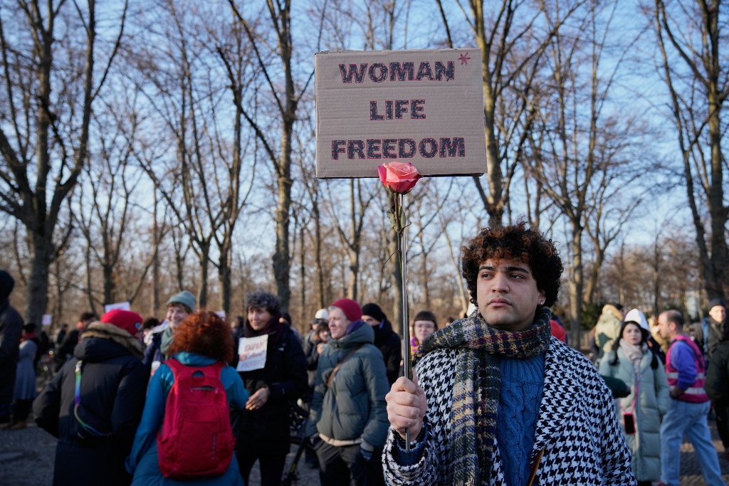Demonstrant håller i ett plakat med texten kvinna, liv, frihet, på engelska.
