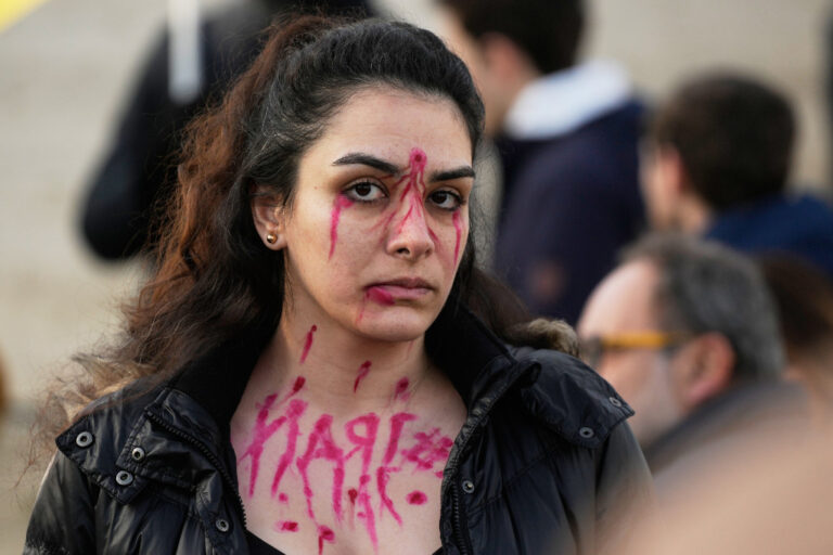 Kvinna med mörkt hår och svart jacka har målat ett kulhål i rött i pannan.