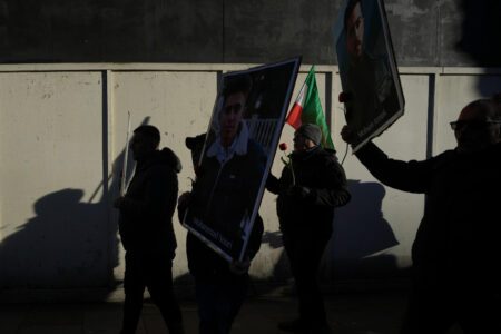 Demonstranter i London håller upp plakat på två unga män, fotade i skugga.