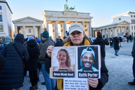 Kvinna håller upp foton på Renee Nicole Good och Keith Porter.