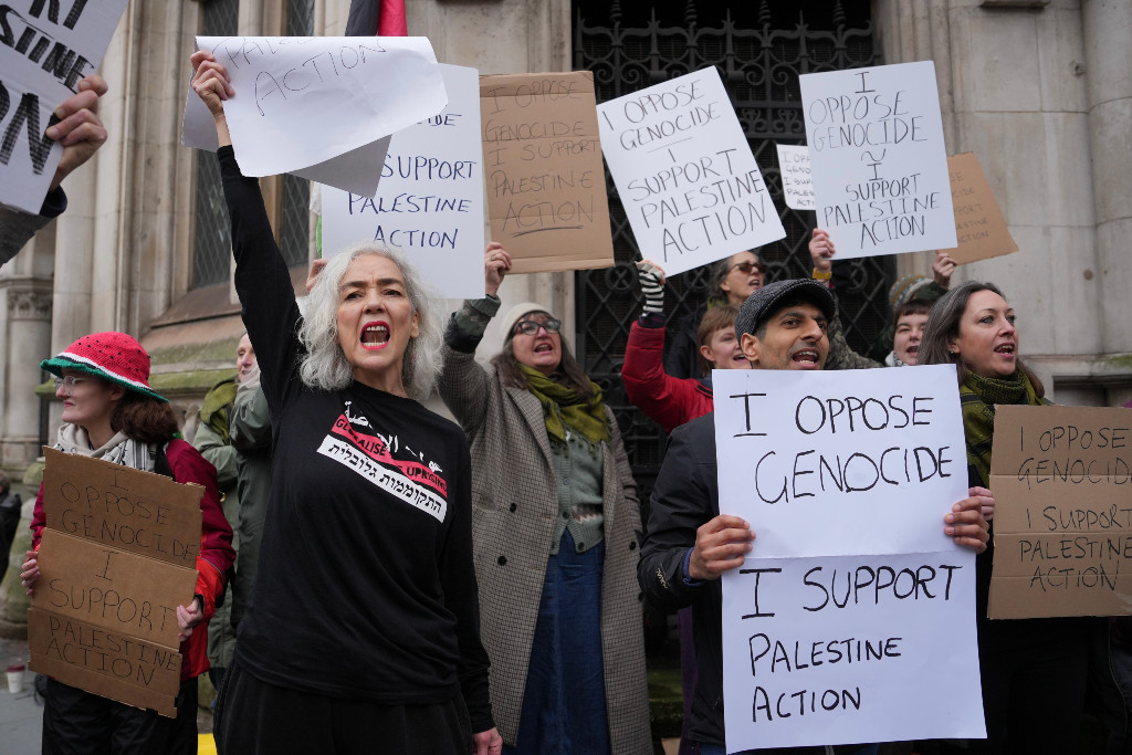 Flera personer håller upp handskrivna plakat.