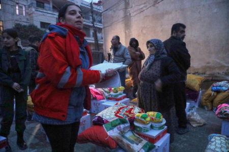 Kvinna i röd jacka ger hjälp till familjer på flykt.