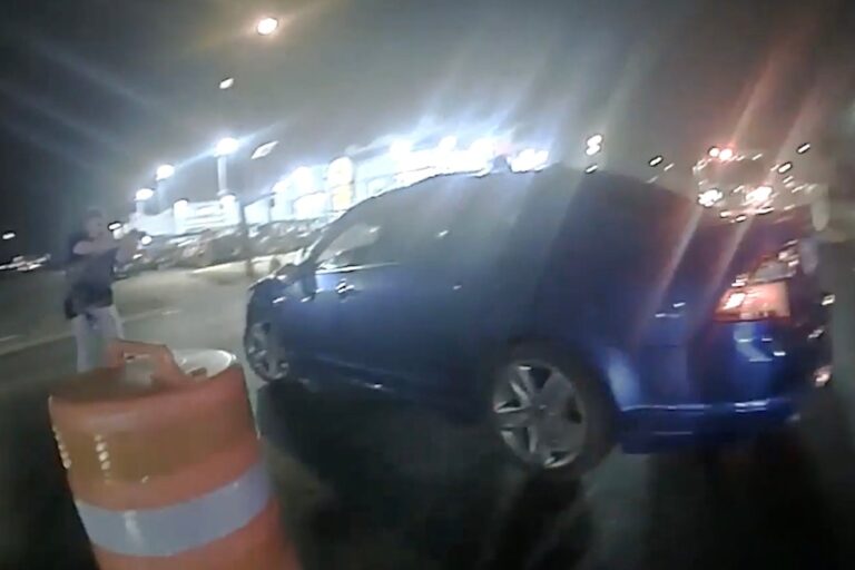 En man riktar sitt vapen mot en blå bil nattetid.