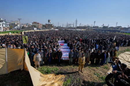 Människor deltar i en begravningsbön utomhus för flera personer som dödats i en terrorattack.