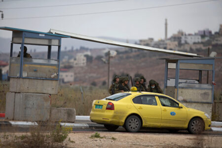 Gul bil har stoppats av soldater vid en vägspärr.