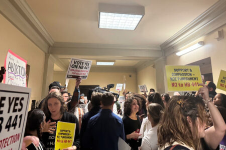 Människor i ett rum håller i plakat för eller emot ett lagförslag om totalförbud mot abort.