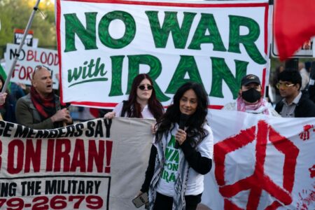 Demonstranter med banderoller protesterar mot kriget i Iran.