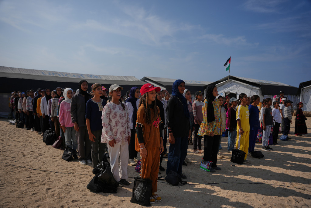 Studenter uppställda på morgonsamling på sandig jord.
