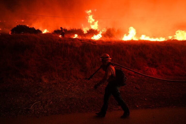 Brandman, i bakgrunden stora flammor från skogsbrand.
