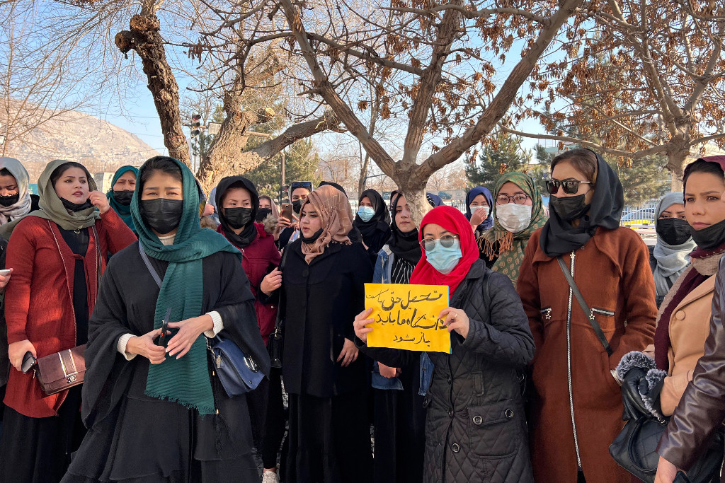 Afghanska kvinnor protesterar med litet plakat.
