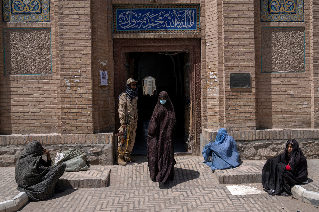 Kvinnor i burqa ber om allmosor vid moské.