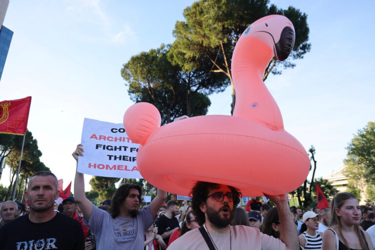 Man i demonstration bär på uppblåsbar flamingo.