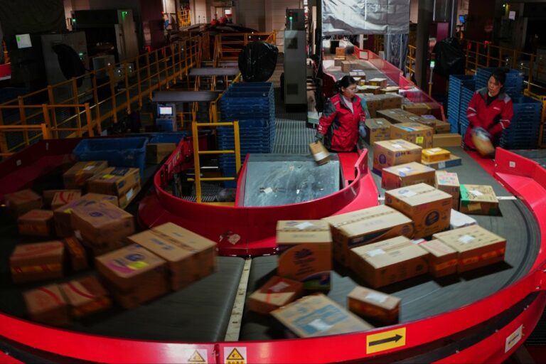 Arbetare sorterar paket vid löpande band.