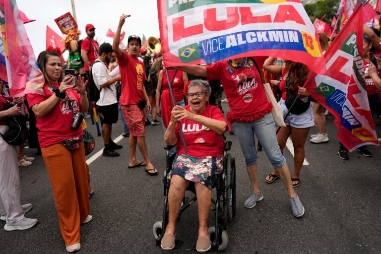 En kvinna i rött och i rullstol och andra supportrar till Lula.
