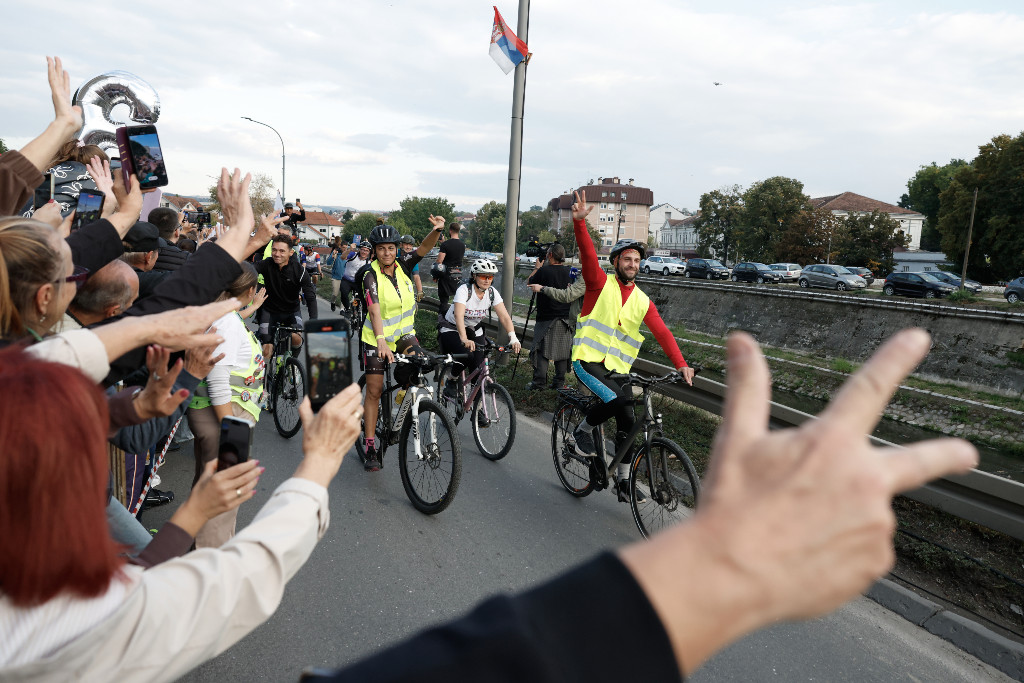 Människor hejar på cyklister och gör segertecken.