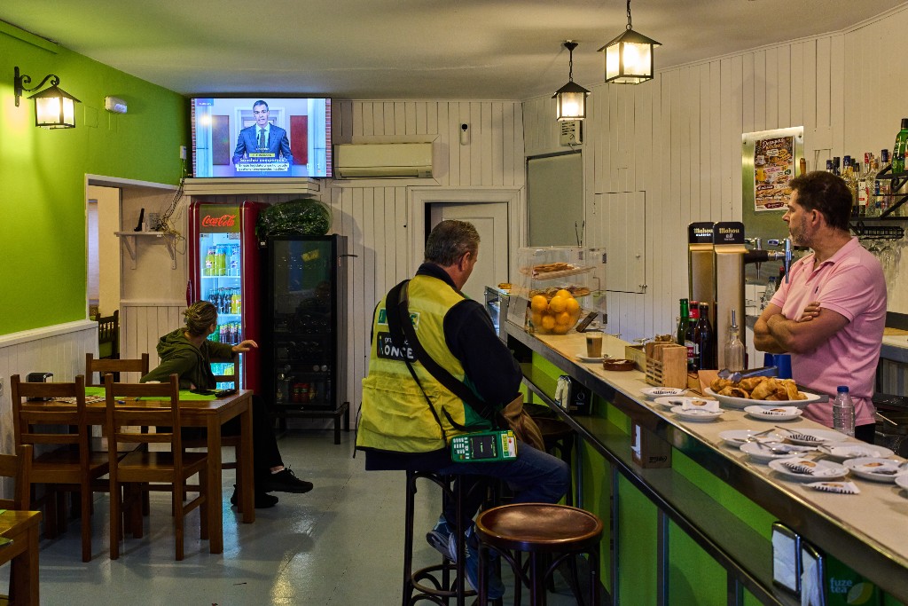 Två personer tittar på tv i en bar.