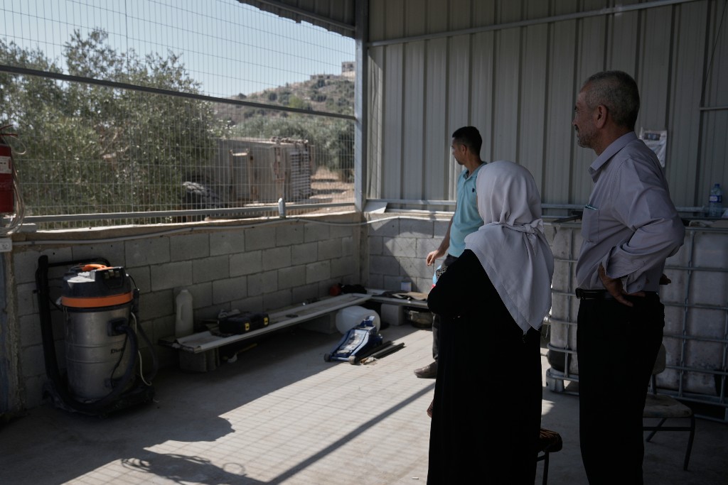 En palestinsk ser på när en israelisk bulldozer drar upp deras olivträd med rötterna.