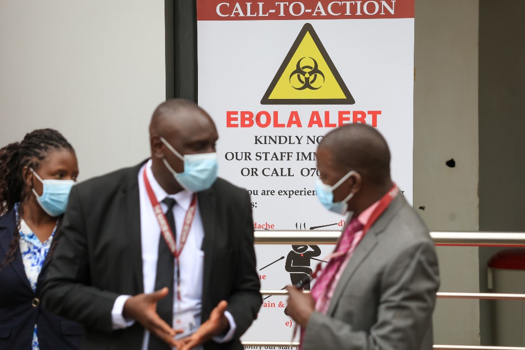 Tre personer står med munskydd utanför en ebola-avdelning på ett sjukhus.