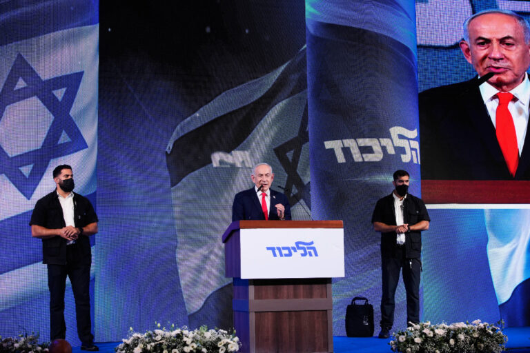 Benjamin Netanyahu vid talarstol med israeliska flaggor.